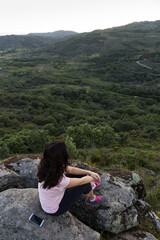 Naklejka na ściany i meble Woman sitting on rock observing landscape