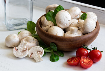 Champignons with herbs and cherry tomatoes on the white wooden background