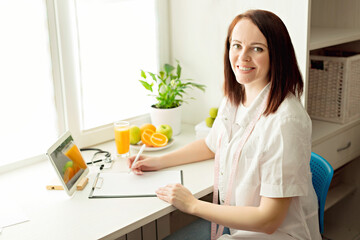 Beautiful woman nutritionist doctor working in her bright, sunny office at the clinic, makes an...
