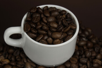 White mug with coffee grains sprinkled with coffee grains on a background