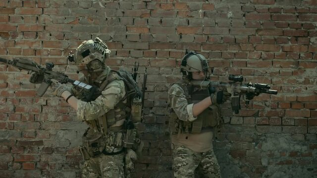 Airsoft men back to back look around the corner with gun. Training to fight in urban territory. Tactics rules
