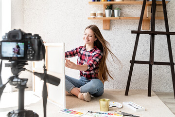 Young artist woman blogger making a video for her blog on art painting a picture
