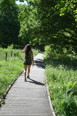 Fototapeta na wymiar Woman walking on footpath at Askham Bog near York, England, UK