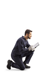 Auto mechanic worker in a uniform kneeling and writing a document