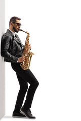 Handsome young male musician in a leather jacket playing a saxophone
