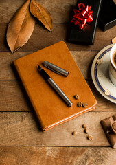  Delicious Coffee on the wooden table with stylish notebook,pen and chocolate.Conceptual image of celebrations.
