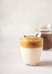 Dalgona coffee, a trendy drink. Glasses of Dalgona coffee and a can of instant coffee stand on a gray concrete table. Vertical orientation, there is a copy space.