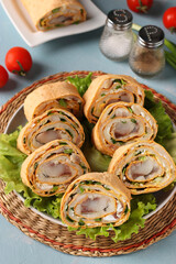 Pita roll with herring, potatoes and onions on light blue background, vertical format, closeup