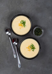 Vegan corn soup puree with oatmeal cream in a bowl on a dark background top view