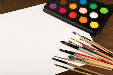 art background with paint brushes and color paints top view with copy space.