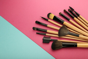 Obraz na płótnie Canvas set of professional makeup brushes and products on pink multicolored background top view