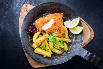 Traditionelles frittiertes Steak vom Kalb mit Bratkartoffel und Preiselbeer Sauce angeboten als...