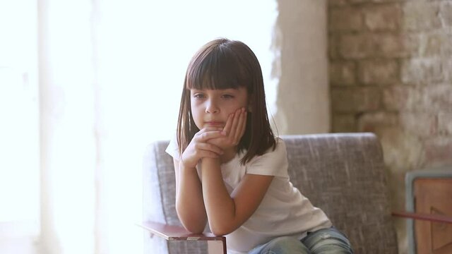 Six years old daughter sit on chair at home feels resent about punishment of parents, kid girl waiting suffer from boredom thinking lost on sad thoughts, little person problems frustrations concept