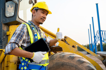 Construction worker with backhoe loader on the background at construction site.