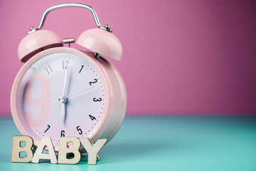 Time to baby. Detail close up of the old pink vintage alarm clock on colour background.