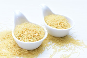 Short pasta spaghetti angel hair displayed in containers on white background