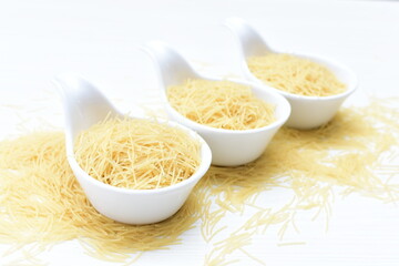 Short pasta spaghetti angel hair displayed in containers on white background
