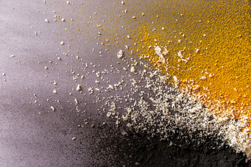 Colorful explosion of three ingredients: activated carbon, coconut and turmeric on grey background