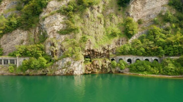 Flight along Grumo tunnel in granite mountain with green trees next to Como Lake, Lecco, Italy 