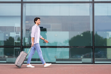 Vacations and travel concept. Man walking with luggage suitcase at airport