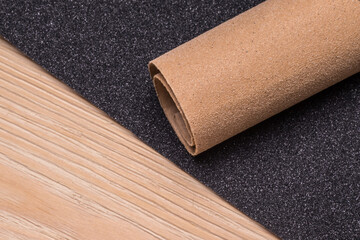 Roll and a sheet of sandpaper on a wooden surface