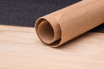 Roll and a sheet of sandpaper on a wooden surface