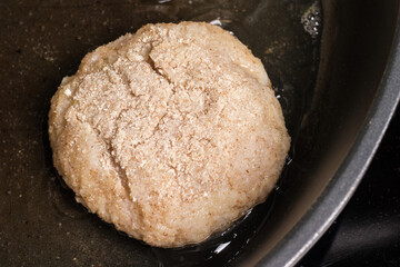 Chicken cutlet in a pan, the beginning of the cooking process.