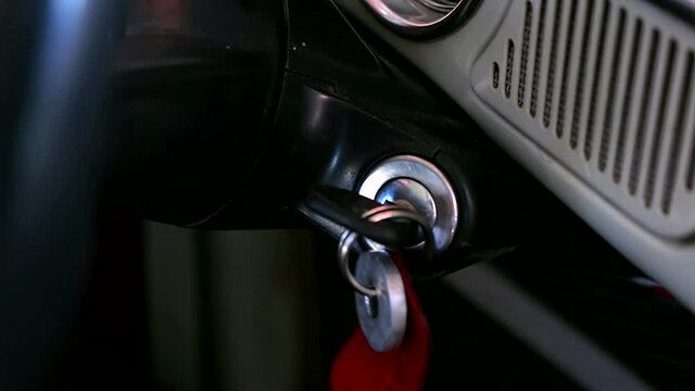 Man turns the key in the ignition lock of the old retro car