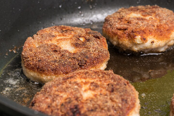 Fototapeta na wymiar Roasted chicken cutlets in a pan. Frying process, selective focus