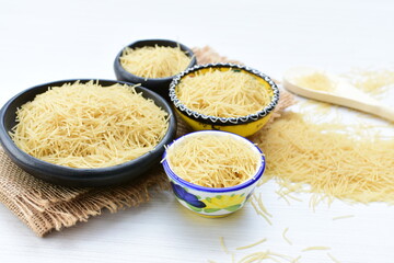 Short pasta spaghetti angel hair displayed in containers on white background