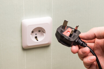 Different standards for electrical outlets. Unsuitable connector and plug in the hand of a person....