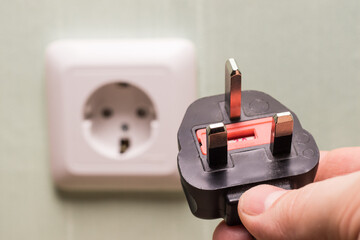 Different standards for electrical outlets. Unsuitable connector and plug in the hand of a person....
