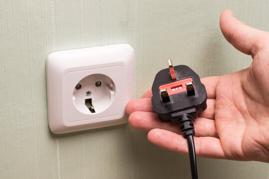 Different standards for electrical outlets. Unsuitable connector and plug in the hand of a person. Incompatibility, concept