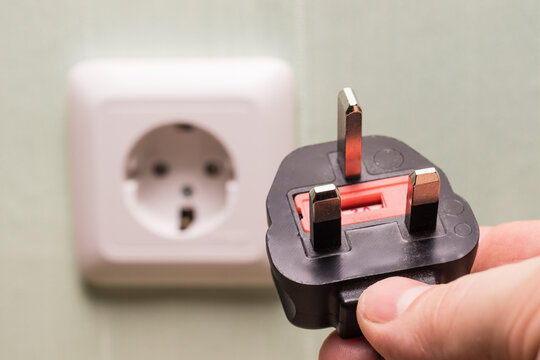 Different standards for electrical outlets. Unsuitable connector and plug in the hand of a person. Incompatibility, concept