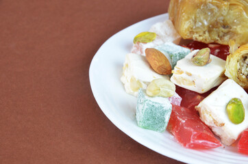 Tasty oriental sweets baklava, turkish delight on a plate on a dark black brown background