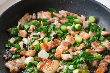 Fatty pork with green onions fried in a pan. Copy space.
