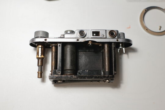 Disassembled vintage camera on a white table. Repair an old analog film camera. Selective focus.
