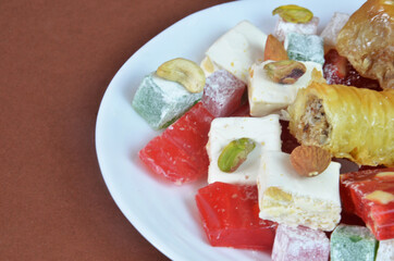 Tasty oriental sweets baklava, turkish delight on a plate on a dark black brown background