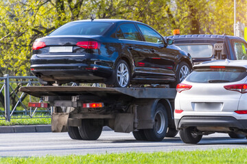 Passenger car loaded onto an evacuation truck rides along the road.