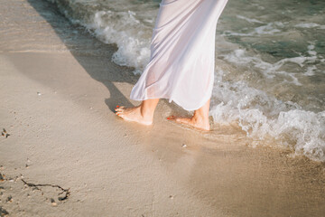 Bride walking on the beach barefoot stepping in the water. High quality photo
