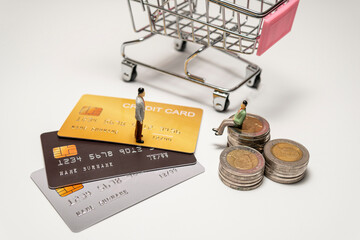 Miniature figure businessman standing on credit card and sitting on stacked coin and cart on back....