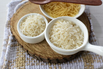 Short pasta spaghetti angel hair and uncooked rice displayed in containers on white background