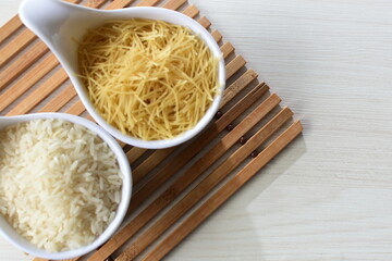 Short pasta spaghetti angel hair and uncooked rice displayed in containers on white background