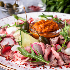 Veal roast beef slices with vegetables on a plate. Closeup.