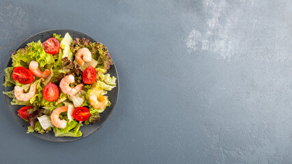 Diet salad with shrimps, tomatoes and mixed greens on a plate.. Healthy food. Top view, text space