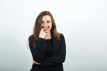 Young attractive brunette woman in a black t-shirt and sweater on white background, seductive female touches her finger to the lips. Flirtatious people