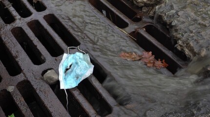 Coronavirus waste. Covid-19 trash. During rain used discarded mask swept into city storm drains and...