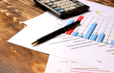 Charts, calculator, pen for writing on the table; business concept