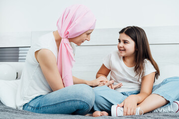 mother with cancer wears a pink headscarf explaining the disease to her daughter