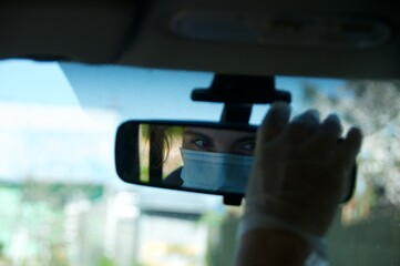 Reflection of face in protective mask in rear view mirror. New normal concept. Pandemic concept. 